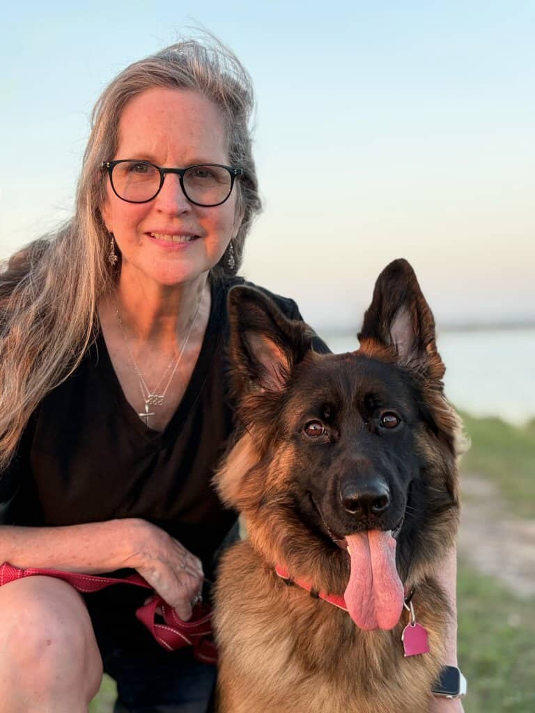 Focus Dog Training Home 1 Woman with glasses and a German Shepherd dog outdoors at sunset.