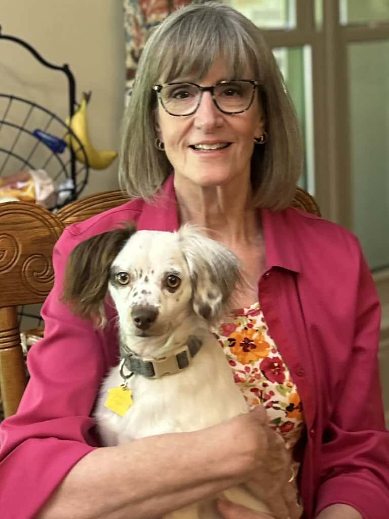 Focus Dog Training Home 1 Woman with glasses holding a small dog in a cozy home setting.